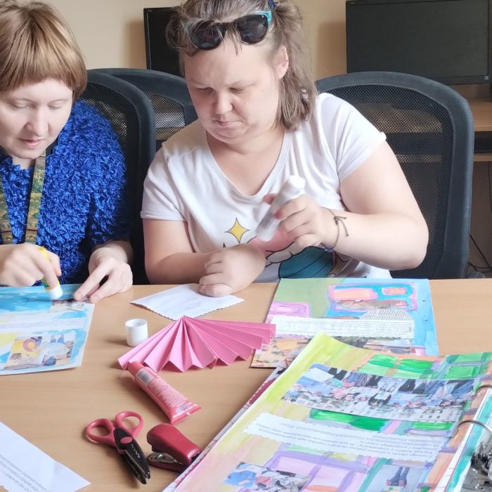 Kobieta wykonuje prace porządkowe i organizuje materiały na regale w pracowni.
