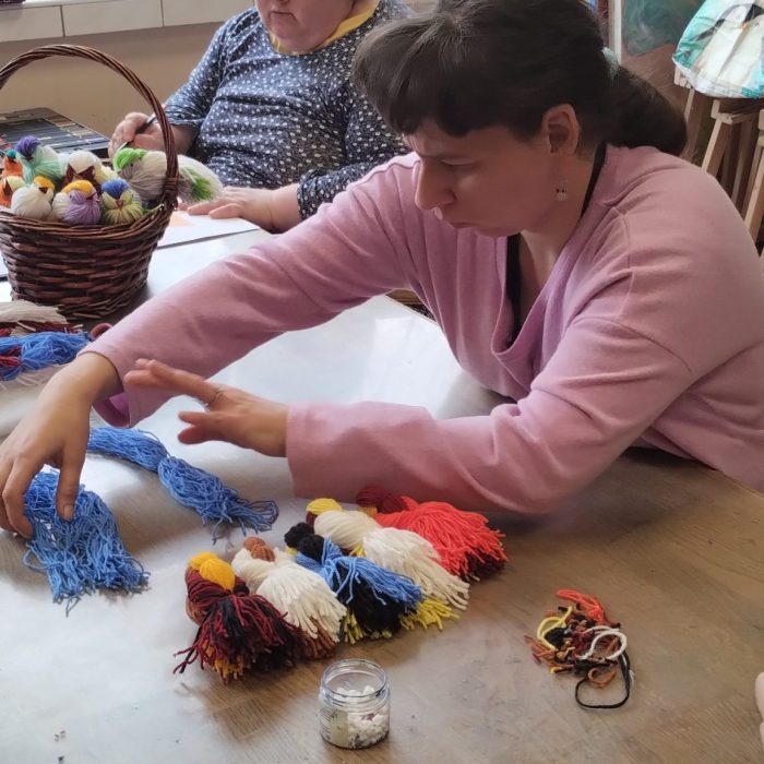 Uczestniczka maluje wielkanocną dekorację farbami podczas zajęć plastycznych.