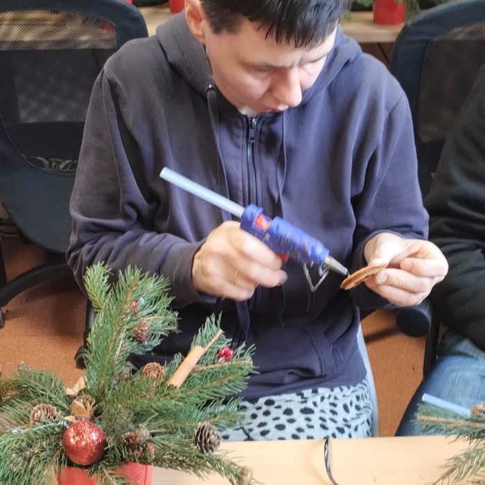Uczestniczka maluje bombkę i przygotowuje świąteczną ozdobę podczas zajęć plastycznych.