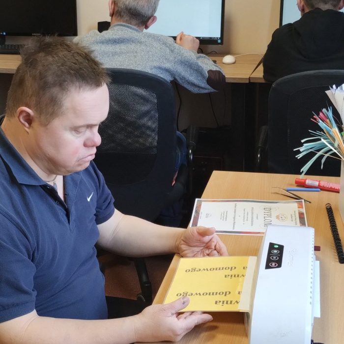Uczestnik maluje świąteczną dekorację przy użyciu farb podczas zajęć plastycznych.