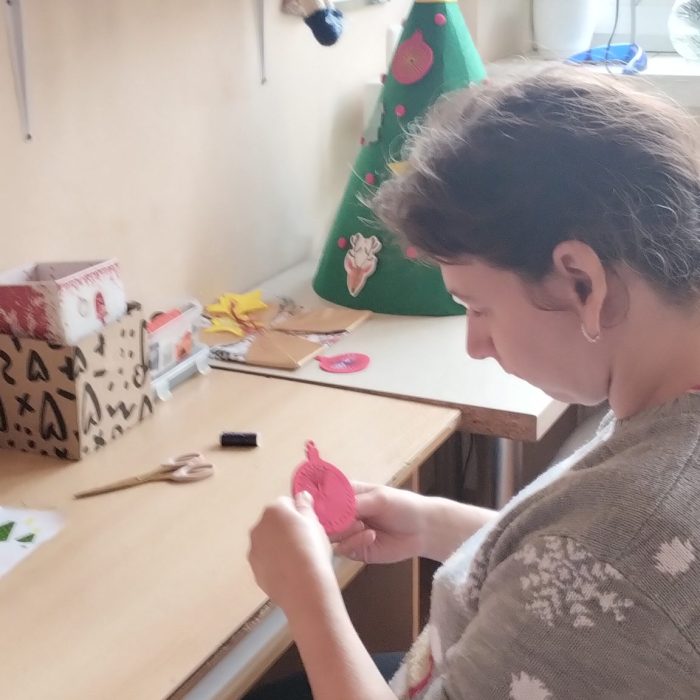 Uczestniczka przygotowuje bombkę do ozdobienia podczas zajęć plastycznych.