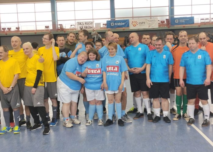 Uczestnik maluje kolorową pracę plastyczną przy użyciu farb podczas zajęć artystycznych.