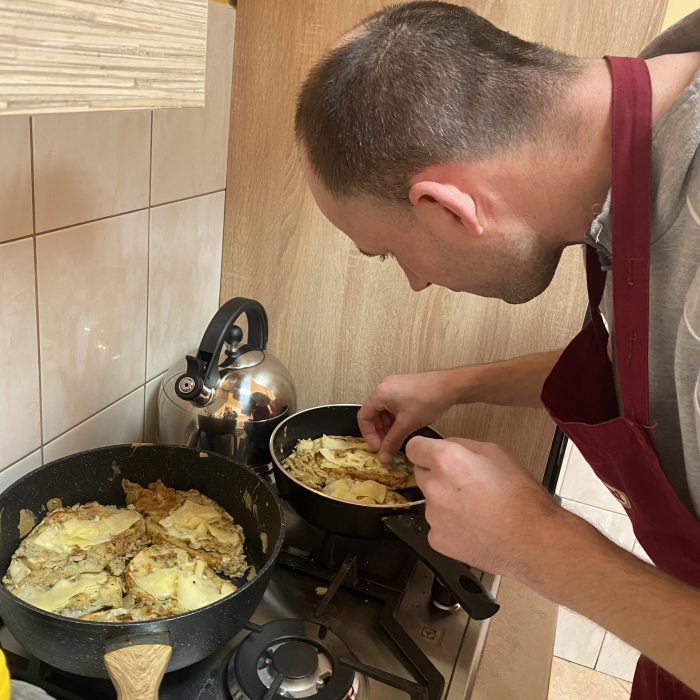 Uczestnicy wspólnie przygotowują posiłek podczas zajęć kulinarnych w pracowni.